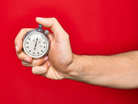 Beautiful hand of man holding stopwatch doing countdown over isolated red background