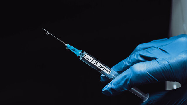 Medical syringe with covid-19 oot vaccine,the inscription coronavirus medicine,the doctor's hand holds the drug from a pandemic,close-up.