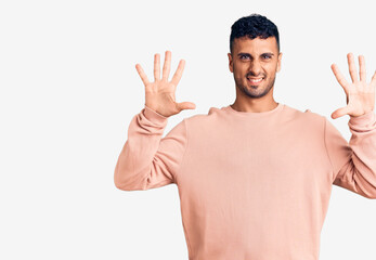 Young hispanic man wearing casual clothes showing and pointing up with fingers number ten while smiling confident and happy.