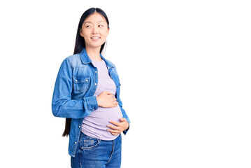 Young beautiful chinese woman pregnant expecting baby looking away to side with smile on face, natural expression. laughing confident.