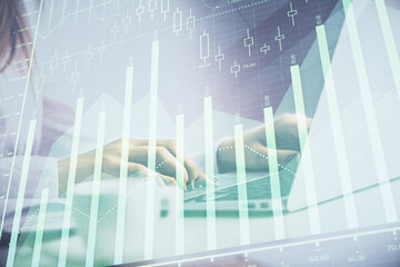 Double exposure of woman hands working on computer and forex graph hologram drawing. Financial analysis concept.