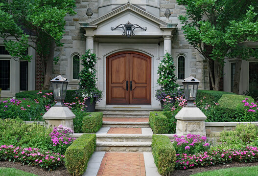 Elegant Wooden Double Front Door Of Stone House, Surrounded By Flowers