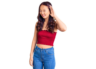 Young beautiful chinese girl wearing casual clothes smiling with hand over ear listening an hearing to rumor or gossip. deafness concept.