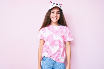 Obraz na płótnie Canvas Cute hispanic child girl wearing casual clothes and funny kitty cap looking positive and happy standing and smiling with a confident smile showing teeth