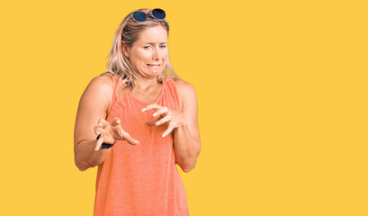 Middle age fit blonde woman wearing casual summer clothes and sunglasses disgusted expression,...