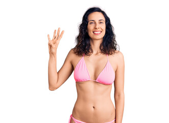 Obraz premium Young beautiful hispanic woman wearing bikini showing and pointing up with fingers number four while smiling confident and happy.