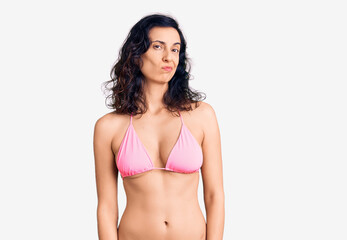 Fototapeta premium Young beautiful hispanic woman wearing bikini looking sleepy and tired, exhausted for fatigue and hangover, lazy eyes in the morning.