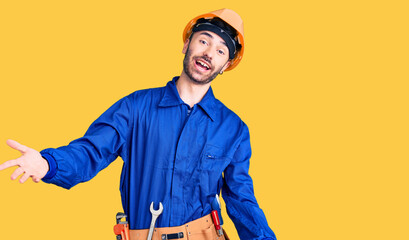 Young hispanic man wearing worker uniform smiling cheerful offering hands giving assistance and acceptance.