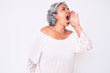 Senior hispanic grey- haired woman wearing casual clothes shouting and screaming loud to side with hand on mouth. communication concept.