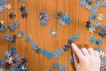 Hand building a jigsaw puzzle and smiley face pattern and shapes. Puzzle piece background and copy space
