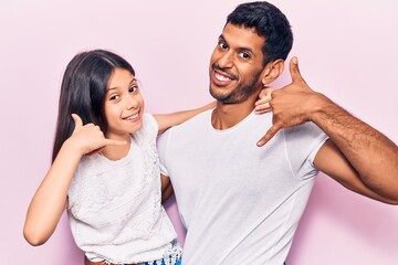 Young father and daughter wearing casual clothes smiling doing phone gesture with hand and fingers like talking on the telephone. communicating concepts.