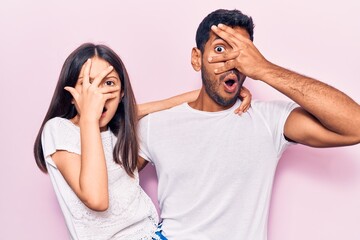 Young father and daughter wearing casual clothes peeking in shock covering face and eyes with hand, looking through fingers with embarrassed expression.