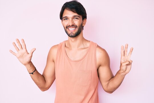 Handsome hispanic man wearing casual clothes showing and pointing up with fingers number eight while smiling confident and happy.