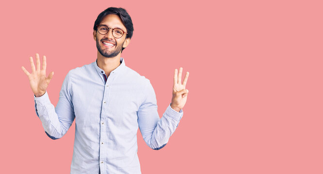 Handsome hispanic man wearing business shirt and glasses showing and pointing up with fingers number eight while smiling confident and happy.