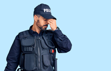 Young hispanic man wearing police uniform tired rubbing nose and eyes feeling fatigue and headache....
