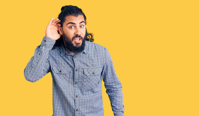 Young arab man wearing casual clothes smiling with hand over ear listening an hearing to rumor or gossip. deafness concept.