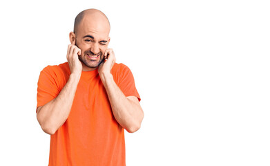 Young handsome man wering casual t shirt covering ears with fingers with annoyed expression for the noise of loud music. deaf concept.