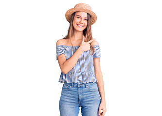 Obraz na płótnie Canvas Young beautiful girl wearing hat and t shirt cheerful with a smile of face pointing with hand and finger up to the side with happy and natural expression on face