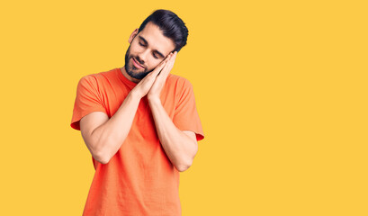 Fototapeta na wymiar Young handsome man with beard wearing casual t-shirt sleeping tired dreaming and posing with hands together while smiling with closed eyes.