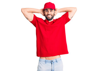 Fototapeta premium Young handsome man with beard wearing delivery uniform relaxing and stretching, arms and hands behind head and neck smiling happy