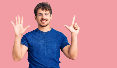 Young handsome man with curly hair wearing casual clothes showing and pointing up with fingers number seven while smiling confident and happy.