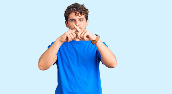 Young handsome man with curly hair wearing casual clothes rejection expression crossing fingers doing negative sign