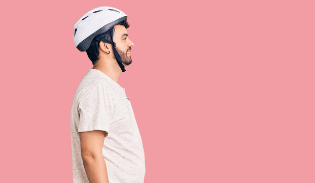 Young hispanic man wearing bike helmet looking to side, relax profile pose with natural face with confident smile.