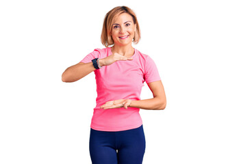 Young blonde woman wearing sportswear gesturing with hands showing big and large size sign, measure symbol. smiling looking at the camera. measuring concept.