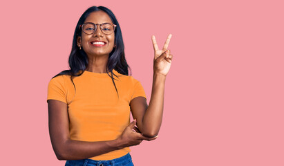 Young indian girl wearing casual clothes and glasses smiling with happy face winking at the camera...