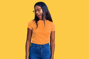 Young indian girl wearing casual clothes and glasses winking looking at the camera with sexy...