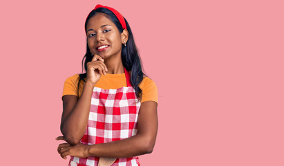 Young indian girl wearing professional baker apron looking confident at the camera with smile with...