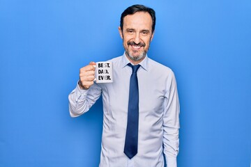 Middle age elegant business man drinking cup of coffee with best dad ever message looking positive and happy standing and smiling with a confident smile showing teeth