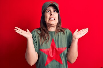Young beautiful brunette woman wearing cap and t-shirt with red star communist symbol clueless and...