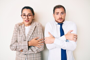 Beautiful couple wearing business clothes shaking and freezing for winter cold with sad and shock expression on face