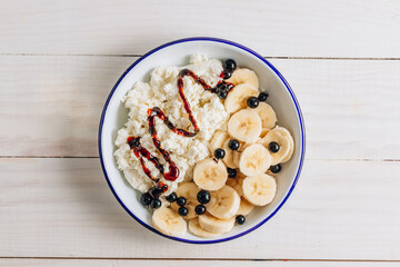 Organic cottage cheese with date syrup and banana for healthy breakfast. White wooden table