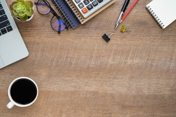 Wooden office desk table with laptop, notebook and coffee cup with equipment other office supplies. 