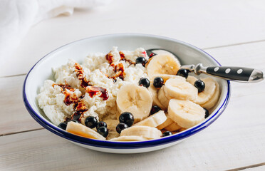 Organic cottage cheese with date syrup and banana for healthy breakfast. White wooden table