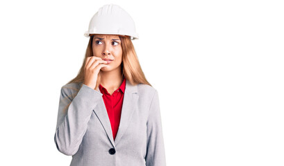 Beautiful young woman wearing architect hardhat looking stressed and nervous with hands on mouth biting nails. anxiety problem.