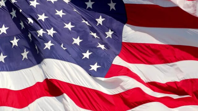 American flag waving in the wind in slow motion, with vibrant red white and blue colors filling the frame completely