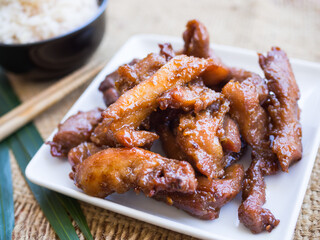 Fried pork on white plate on wood background. Thai food concept.
