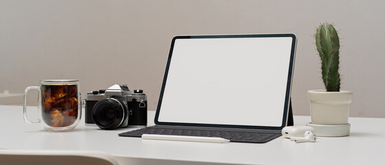 Modern workspace with  mock up tablet, camera, coffee mug and cactus pot on white table