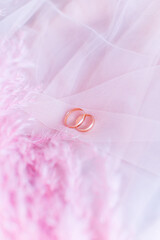 Wedding rings on pink tulle with pink feathers