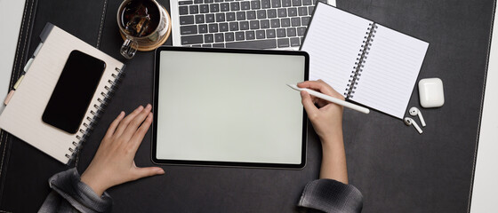 Female using mock up tablet with stylus pen on dark office desk