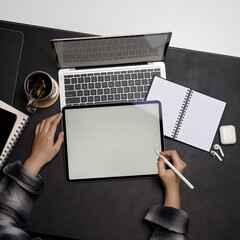 Hands using mock up tablet with stylus pen on dark office desk
