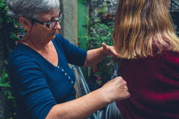 Senior woman cutting young womasns hair