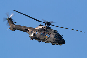 Fototapeta na wymiar Camouflaged military helicopter flying against a blue sky.