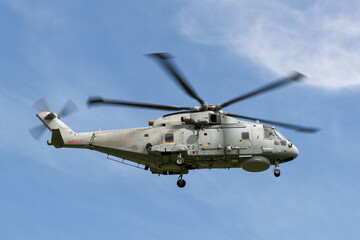 Fototapeta na wymiar Grey military helicopter flying against a blue sky,