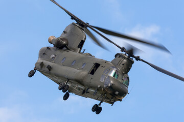 Fototapeta na wymiar Large twin rotor military helicopter maneuvering through the blue sky.