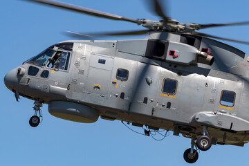 Fototapeta na wymiar Grey military helicopter flying against a blue sky,