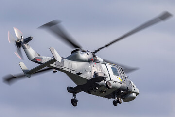 Fototapeta na wymiar Grey camouflaged military helicopter flying.